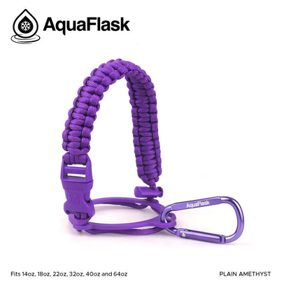 Accesorio de asa de paracord Aquaflask presentado sobre un fondo blanco con el logotipo de Aquaflask. El accesorio está fabricado con paracord firmemente tejido que forma un asa corta. Incluye una hebilla plástica de liberación lateral, un lazo ajustable que se coloca alrededor del cuello de la botella y un mosquetón metálico negro para su sujeción. El producto está etiquetado como compatible con botellas Aquaflask de 14 oz, 18 oz, 22 oz, 32 oz, 40 oz y 64 oz.