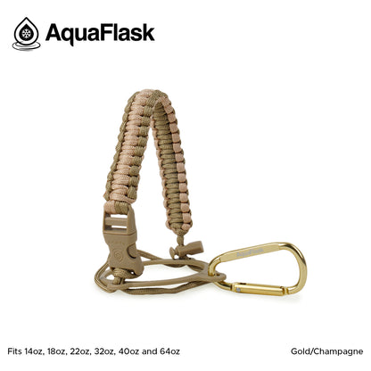 Accesorio de asa de paracord Aquaflask presentado sobre un fondo blanco con el logotipo de Aquaflask. El accesorio está fabricado con paracord firmemente tejido que forma un asa corta. Incluye una hebilla plástica de liberación lateral, un lazo ajustable que se coloca alrededor del cuello de la botella y un mosquetón metálico negro para su sujeción. El producto está etiquetado como compatible con botellas Aquaflask de 14 oz, 18 oz, 22 oz, 32 oz, 40 oz y 64 oz.