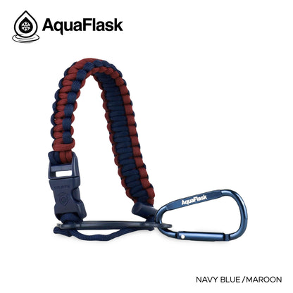Accesorio de asa de paracord Aquaflask presentado sobre un fondo blanco con el logotipo de Aquaflask. El accesorio está fabricado con paracord firmemente tejido que forma un asa corta. Incluye una hebilla plástica de liberación lateral, un lazo ajustable que se coloca alrededor del cuello de la botella y un mosquetón metálico negro para su sujeción. El producto está etiquetado como compatible con botellas Aquaflask de 14 oz, 18 oz, 22 oz, 32 oz, 40 oz y 64 oz.