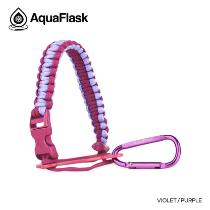 Accesorio de asa de paracord Aquaflask presentado sobre un fondo blanco con el logotipo de Aquaflask. El accesorio está fabricado con paracord firmemente tejido que forma un asa corta. Incluye una hebilla plástica de liberación lateral, un lazo ajustable que se coloca alrededor del cuello de la botella y un mosquetón metálico negro para su sujeción. El producto está etiquetado como compatible con botellas Aquaflask de 14 oz, 18 oz, 22 oz, 32 oz, 40 oz y 64 oz.